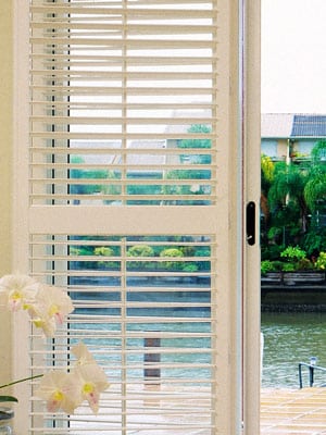 View of window showing outdoor lake, featuring Plantation Shutters by Norman.