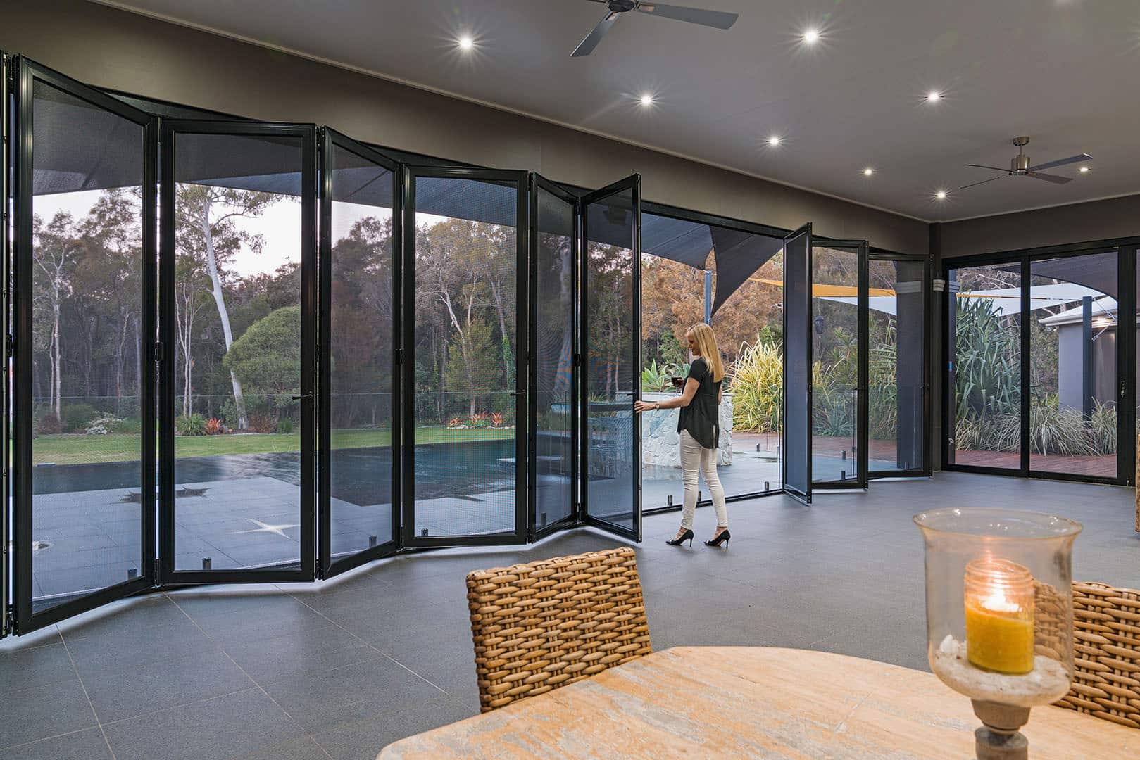 View from inside home to outside patio and swimming pool, separated by Crimsafe glass doors for safety and protection. Installed by Complete Blinds Brisbane.