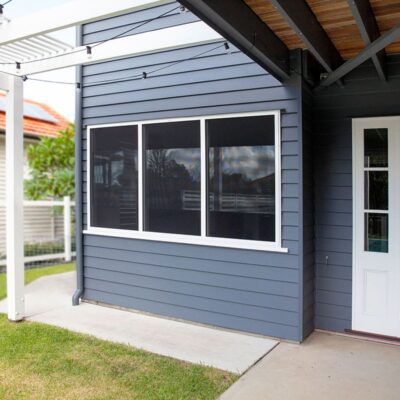 Crimsafe window screen in heritage cream powder-coat frame colour complementing a Brisbane Queenslander home exterior