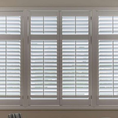Full-height plantation shutters on large living room windows in a Brisbane home showing clean white louvres